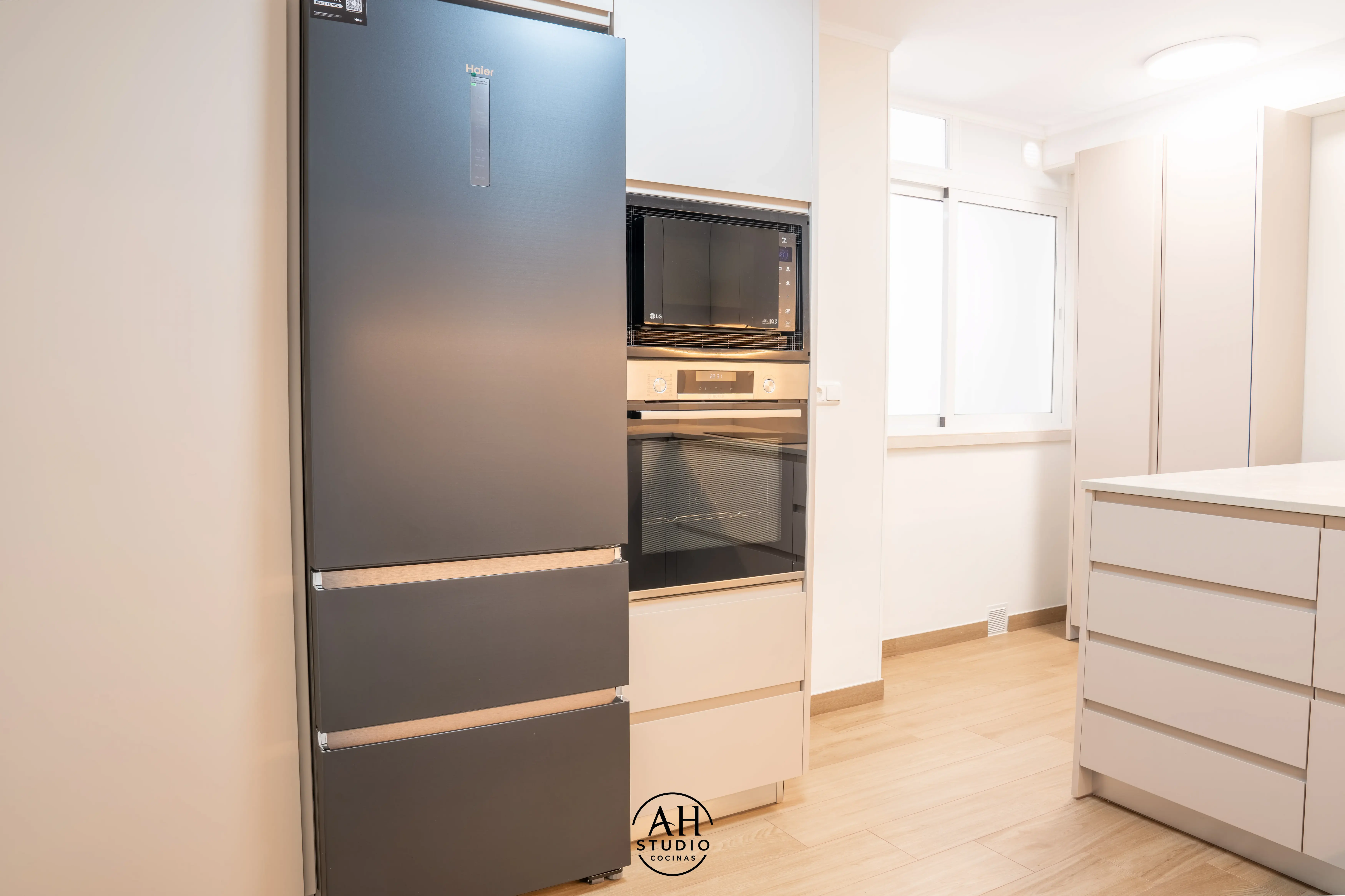 Cocina clara con columna de nevera, horno y microondas y espacio libre a la izquierda