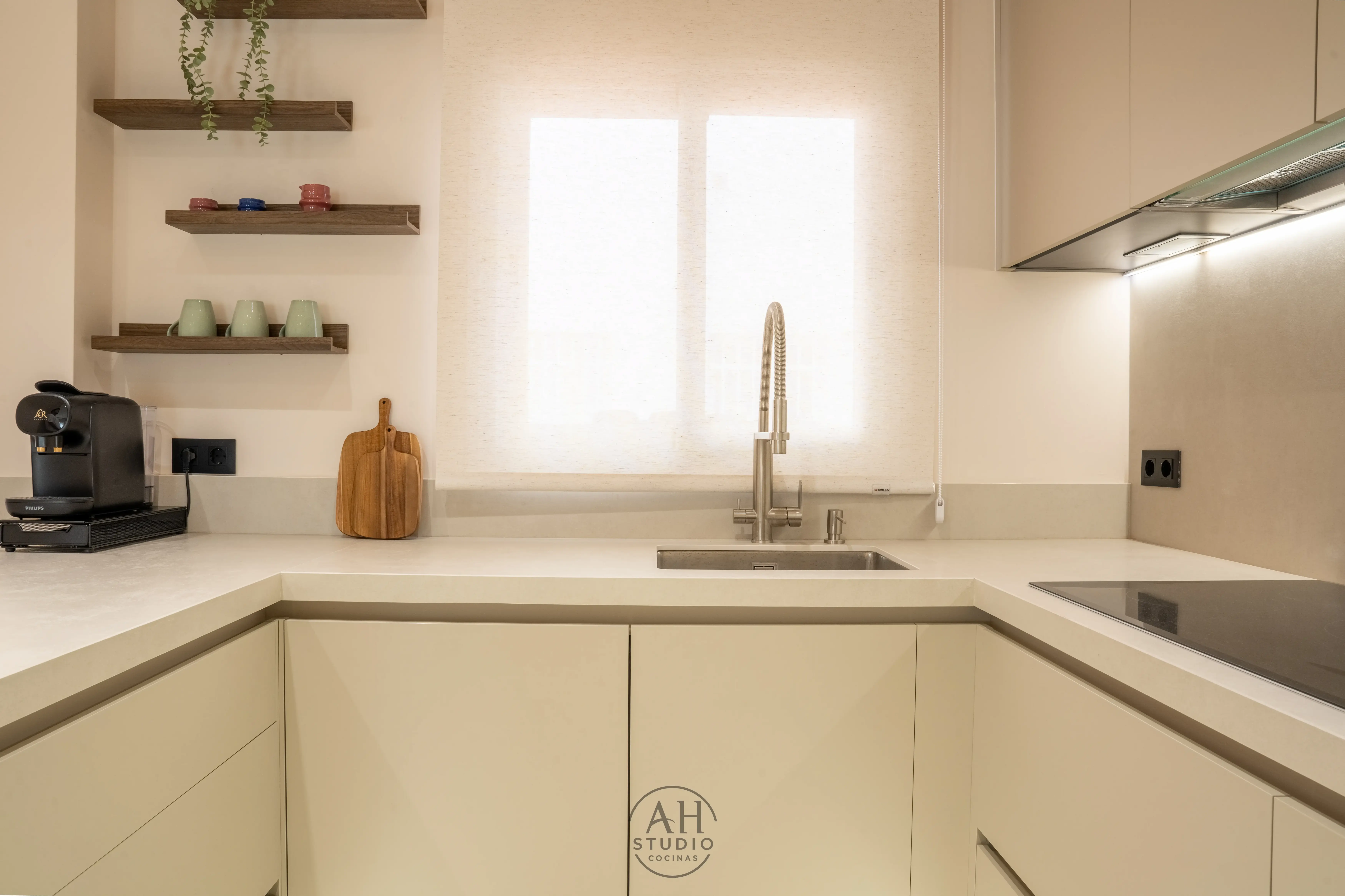 Fregadero crema junto a una ventana, con baldas de madera y encimera
